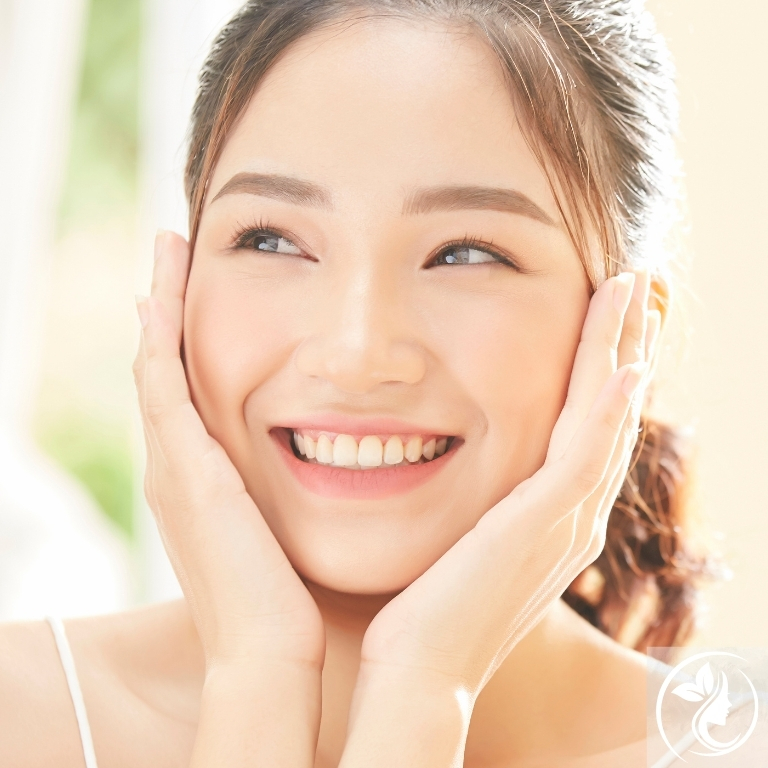 30代女性が明るい笑顔で両手を頬に添える姿。足立区梅島AloHaが紹介するビタミンB群の力でむくみ顔・疲れ顔を改善し、代謝から整える小顔づくりと若見え習慣